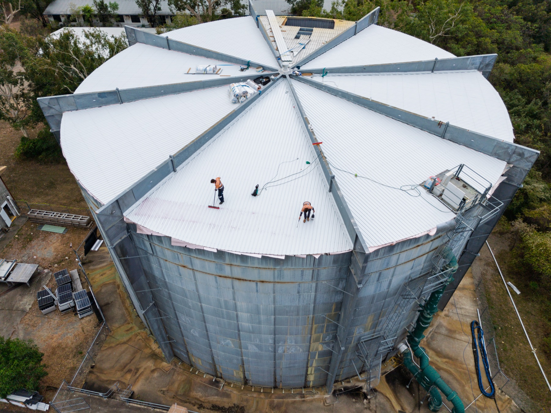 ATM Tanks — Aerial view looking down on the tank roof, its radial steel ribs meeting at the centre, with two workers on the surface for scale