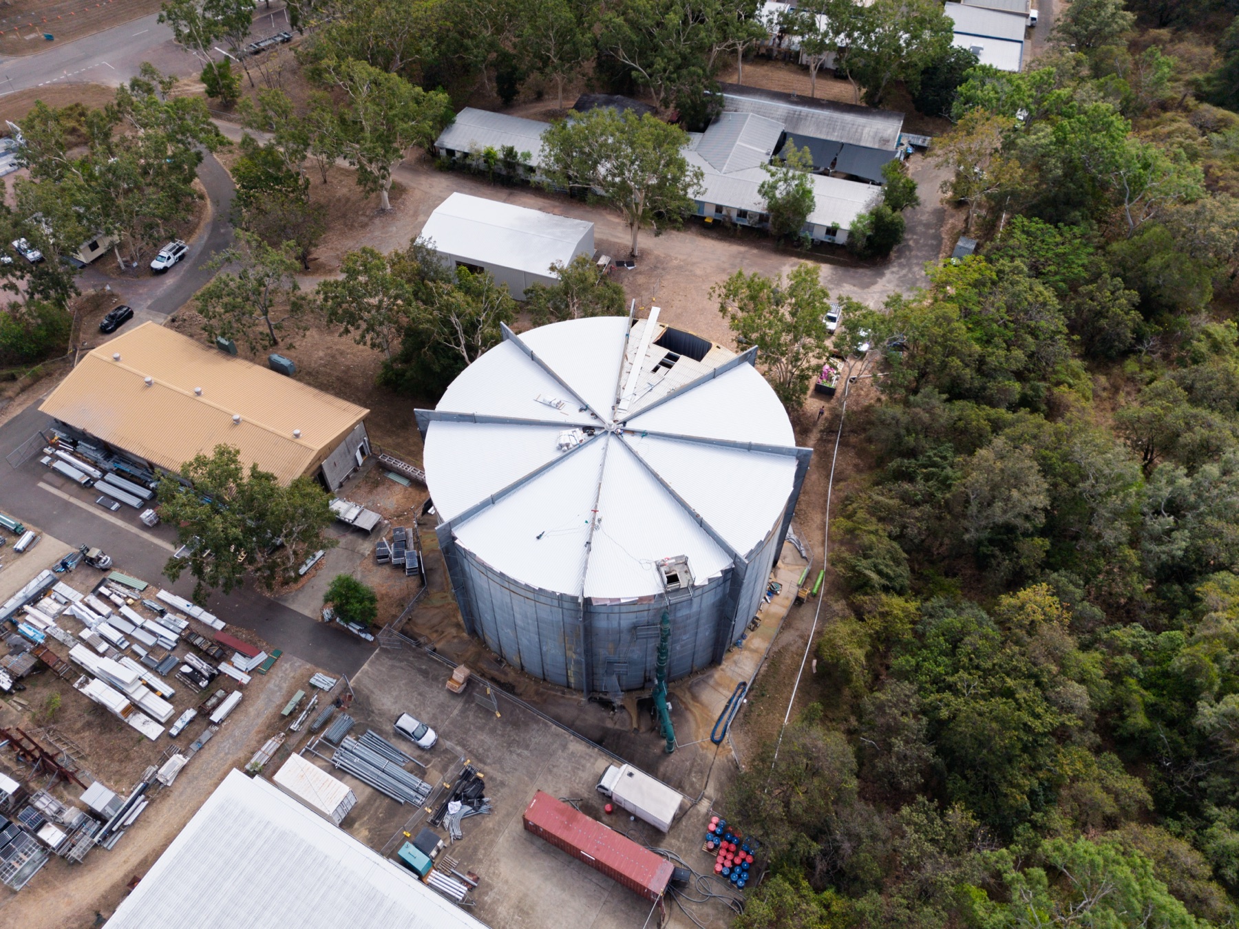 ATM Tanks — Wide aerial of the tank in its full site context, surrounded by sheds, yard stock and bushland
